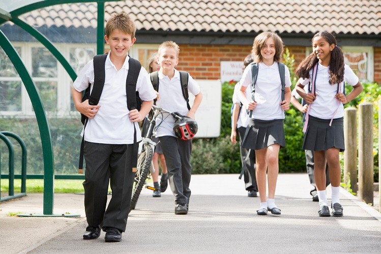 Four students walking towards the camera, with backpacks on.