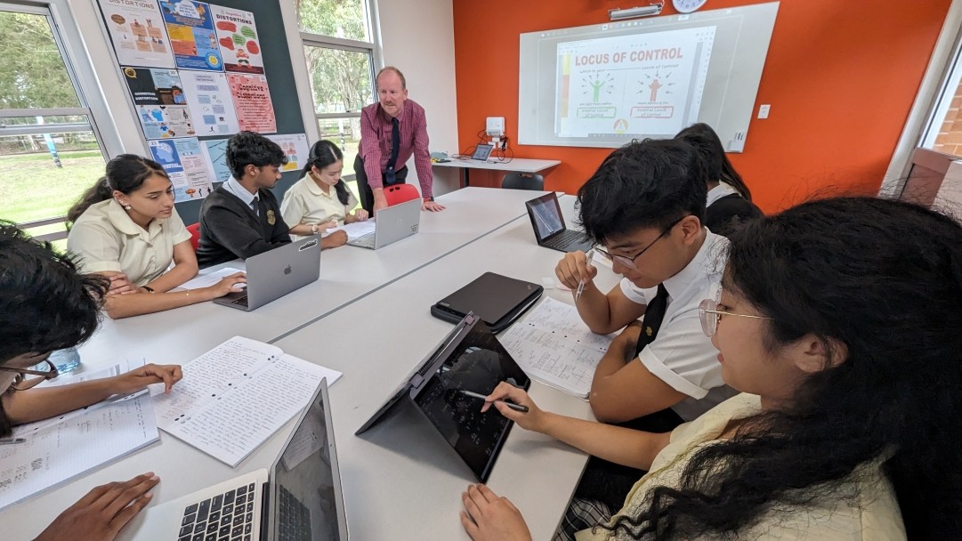 6 high school students being mentored by teacher in a classroom.