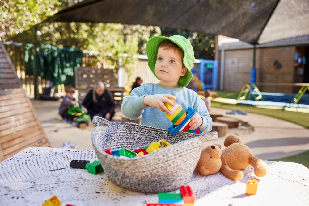Boy playing with plastic blocks outdoors.