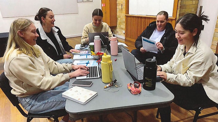 Five educators sit around a rectangular table engaging in a professional learning activity.