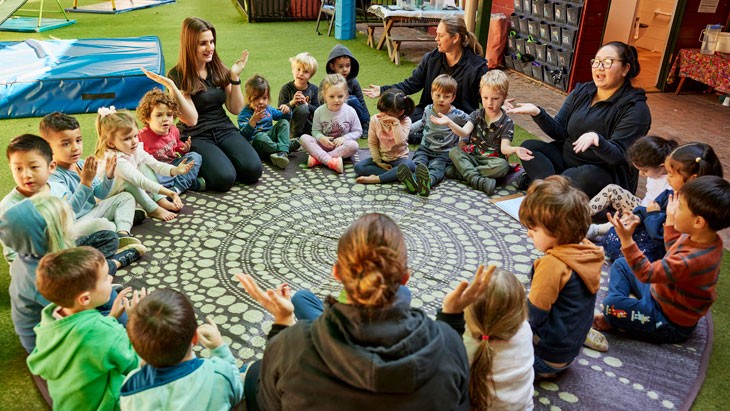 A group of children sitting in a circle with educators.