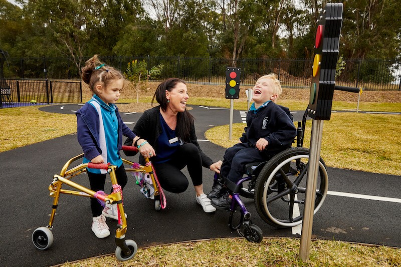 Two primary school students playing outside with a female teacher
