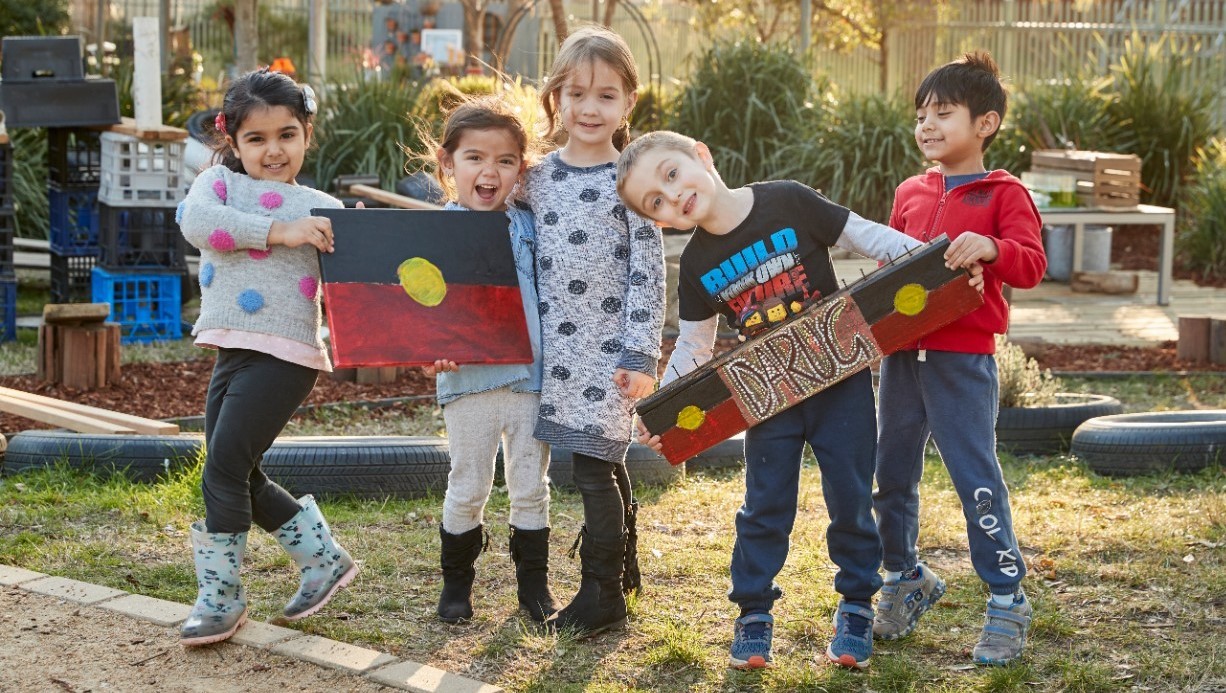 Students standing outside holding Aboriginal flag.