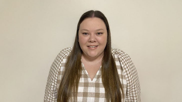 A person with long hair smiling at the camera.