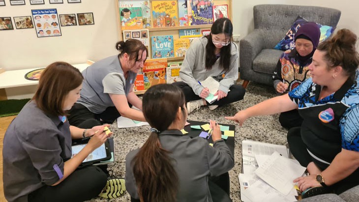  Group of female educators working on the ground talking to each other
