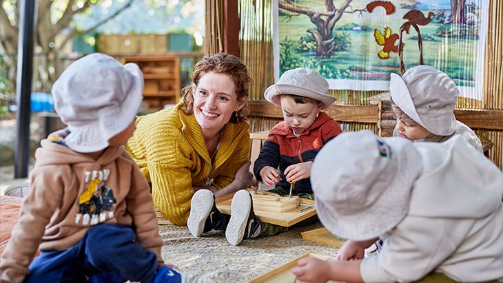 Female educator playing with children outside.