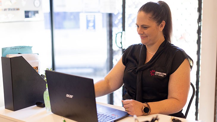 A female educator working at a computer at an early childhood education centre.