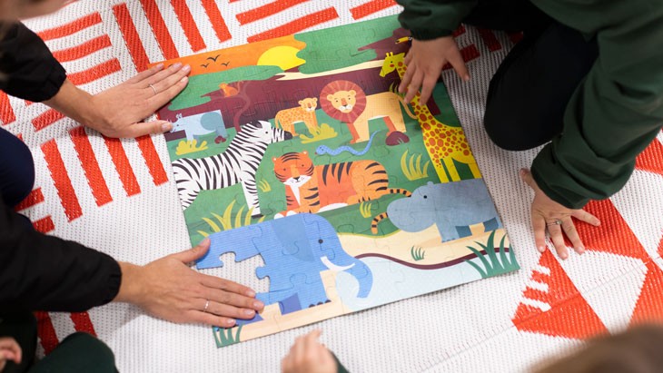 Children playing with a puzzle on a mat.