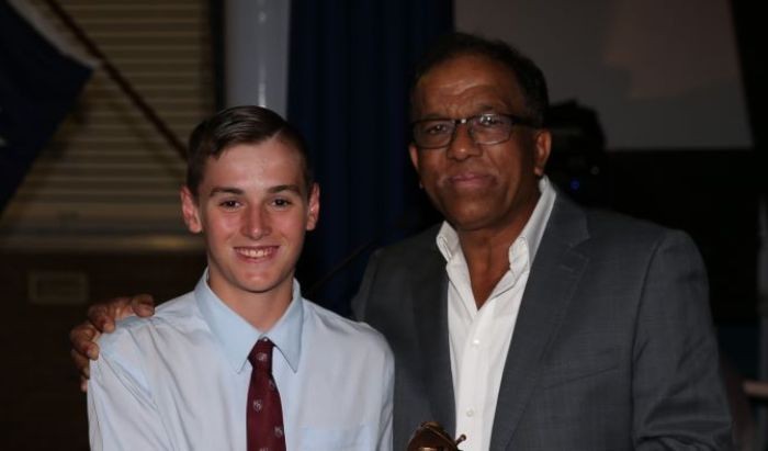 A young white man dressed in a shirt and tie standing with a black man wearing shirt and jacket