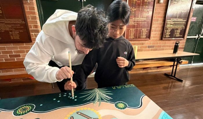 A male teacher and public school boy student doing an Aboriginal painting