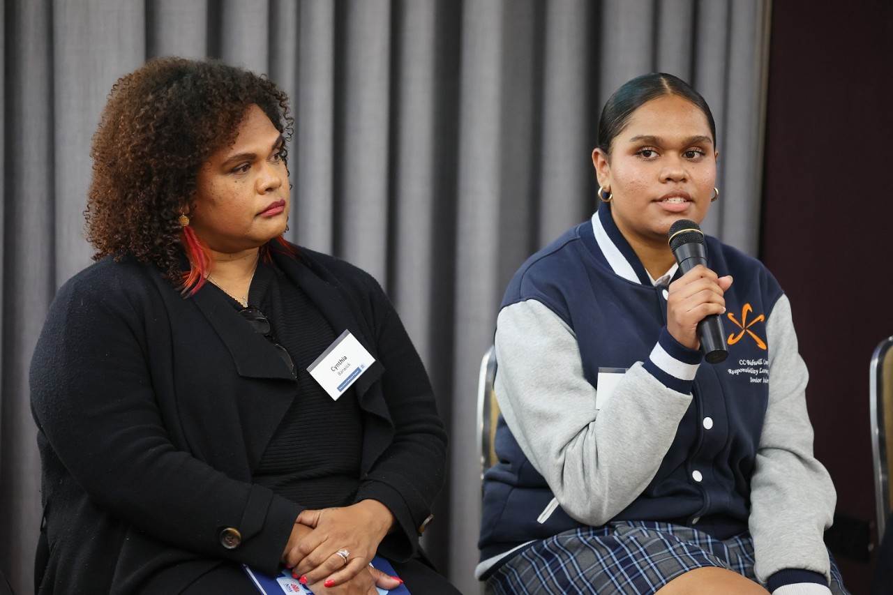 Mother and daughter sitting next to each other, the daughter holding a microphone
