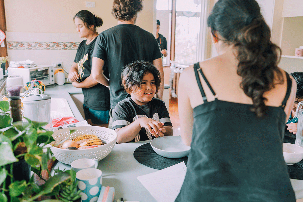 A group of young adults and a child preparing food in a kitchen.