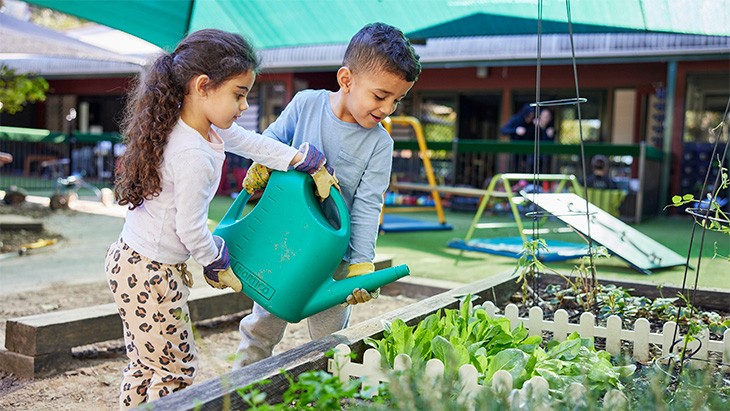 A boy and girl watering plants.