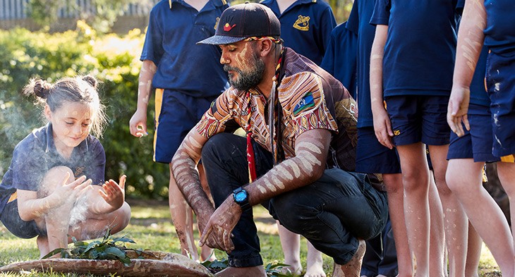 Opportunity Hubs banner - Aboriginal man demonstrating fire making to school children.