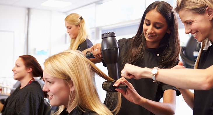 Young female hairdressing trainees on the job.