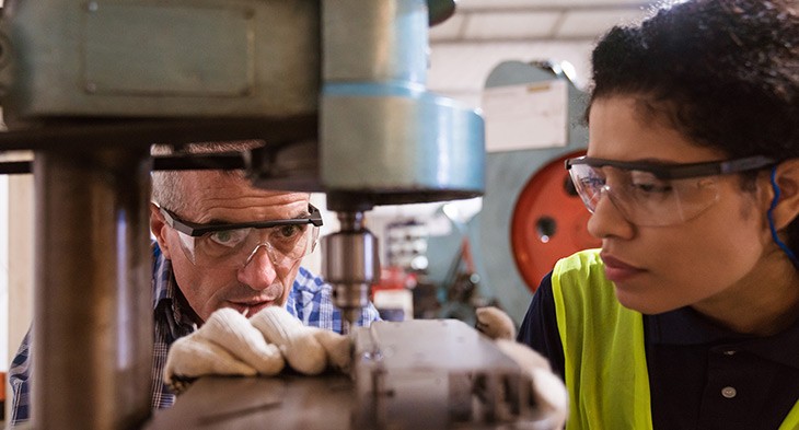 Aboriginal apprentice with supervisor using drill.
