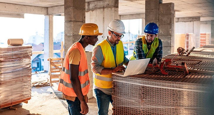 Construction workers looking at laptop.