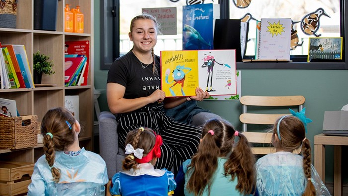 Female early childhood trainee showing children a picture book.