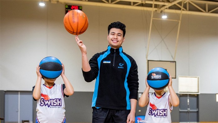 Male coach balancing a basket ball on fingers.
