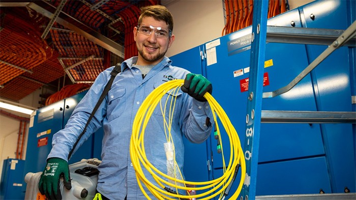 Male electronics apprentice holding cables.