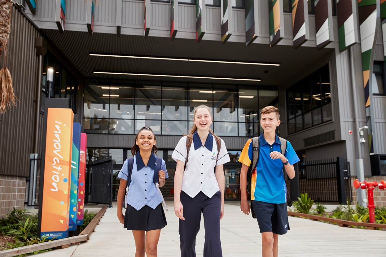 Three students walking outside a school.