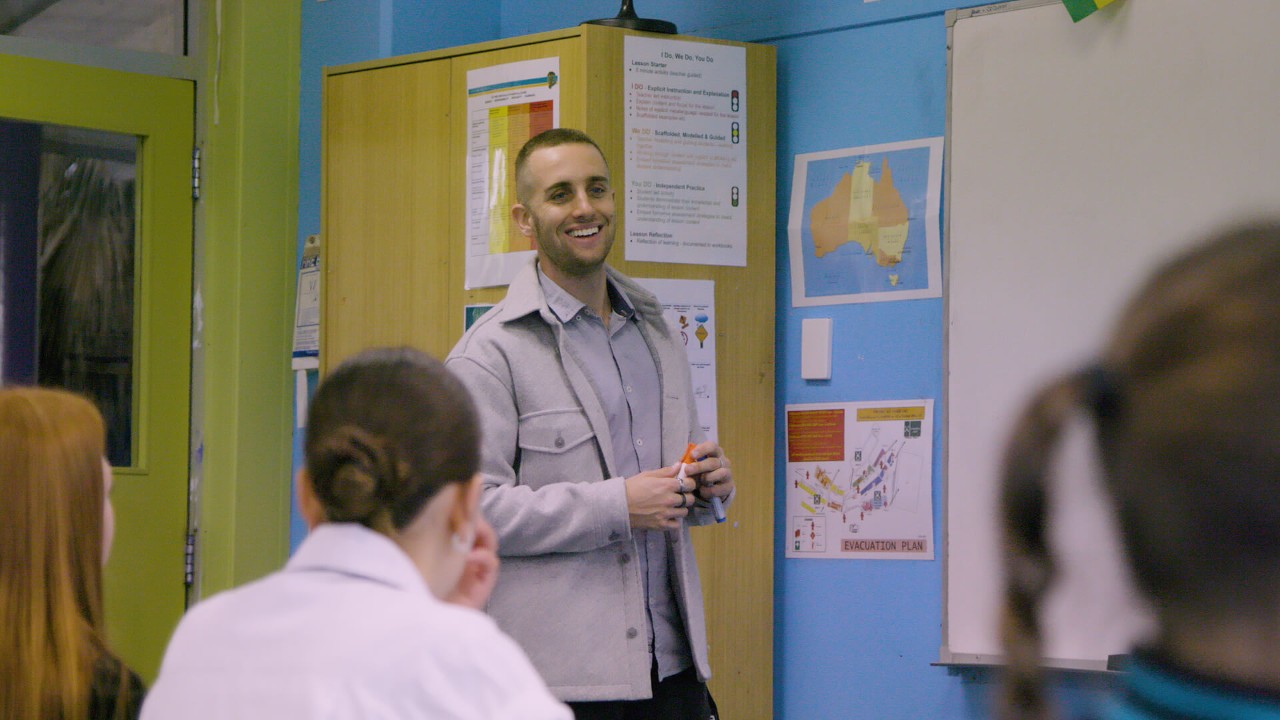 male teacher standing in front of class speaking