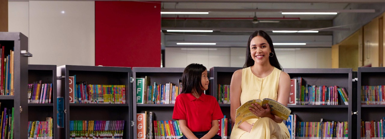 Female teacher reading to student and smiling at camera
