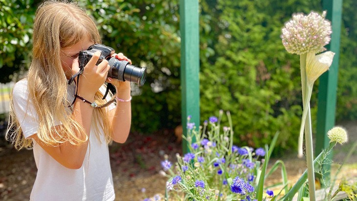 Female student photographing plants outside