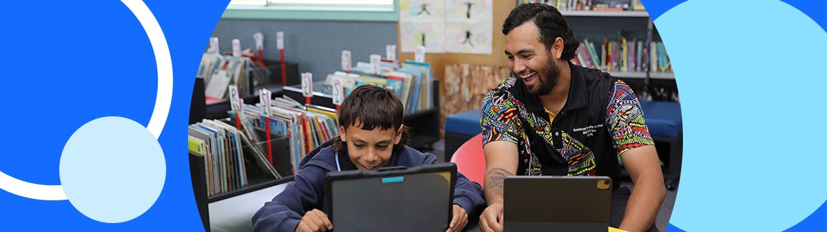 Teacher and student laughing while looking at a laptop.