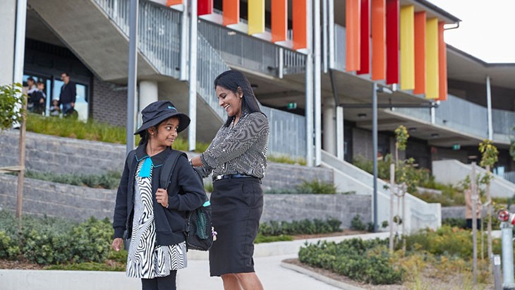 A mother helping her daughter with her backpack when dropping her off at her primary school