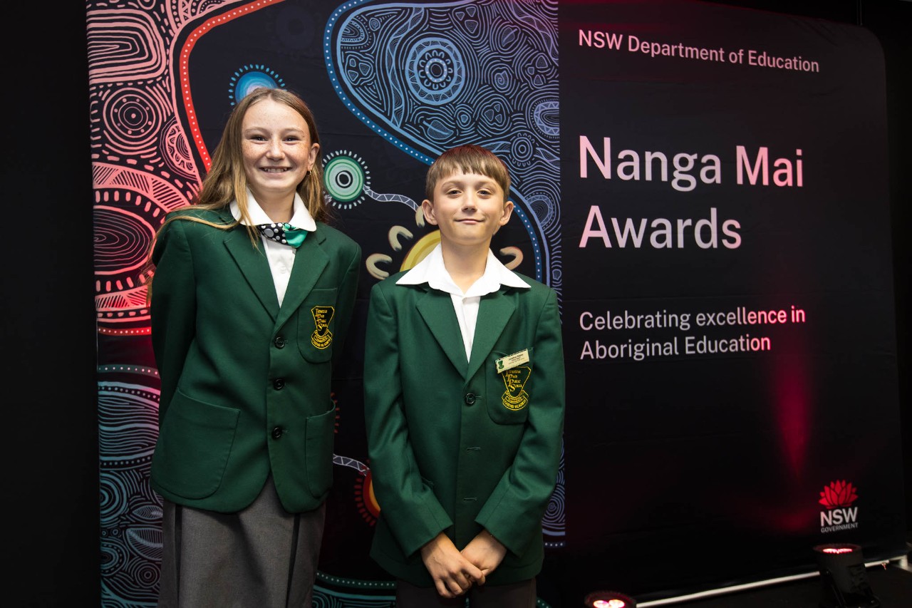 Female and male student in front of banner
