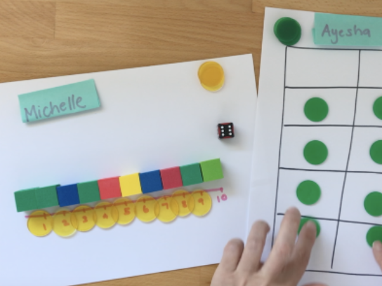 Number train, a line of 10 coloured blocks. The blocks sit above a line counting from 1 to 10. To the right is a ten frame game board, a table 6 cells long and  2 cells wide with green counters on top.