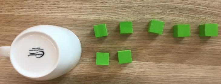 An upside down cup and a row of 5 blocks and a row of 2 blocks below it
