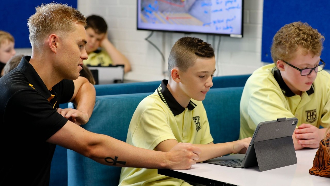 A teacher working with his student on a device