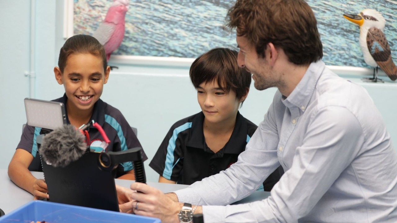 Two students and teacher using a podcasting kit