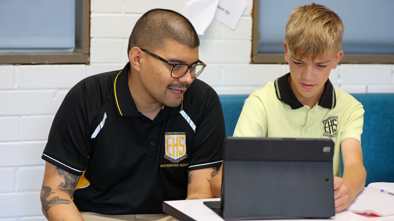 Teacher and student sitting working on an iPad.