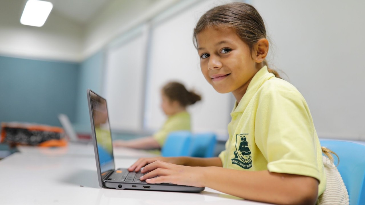 Student on a device smiling.