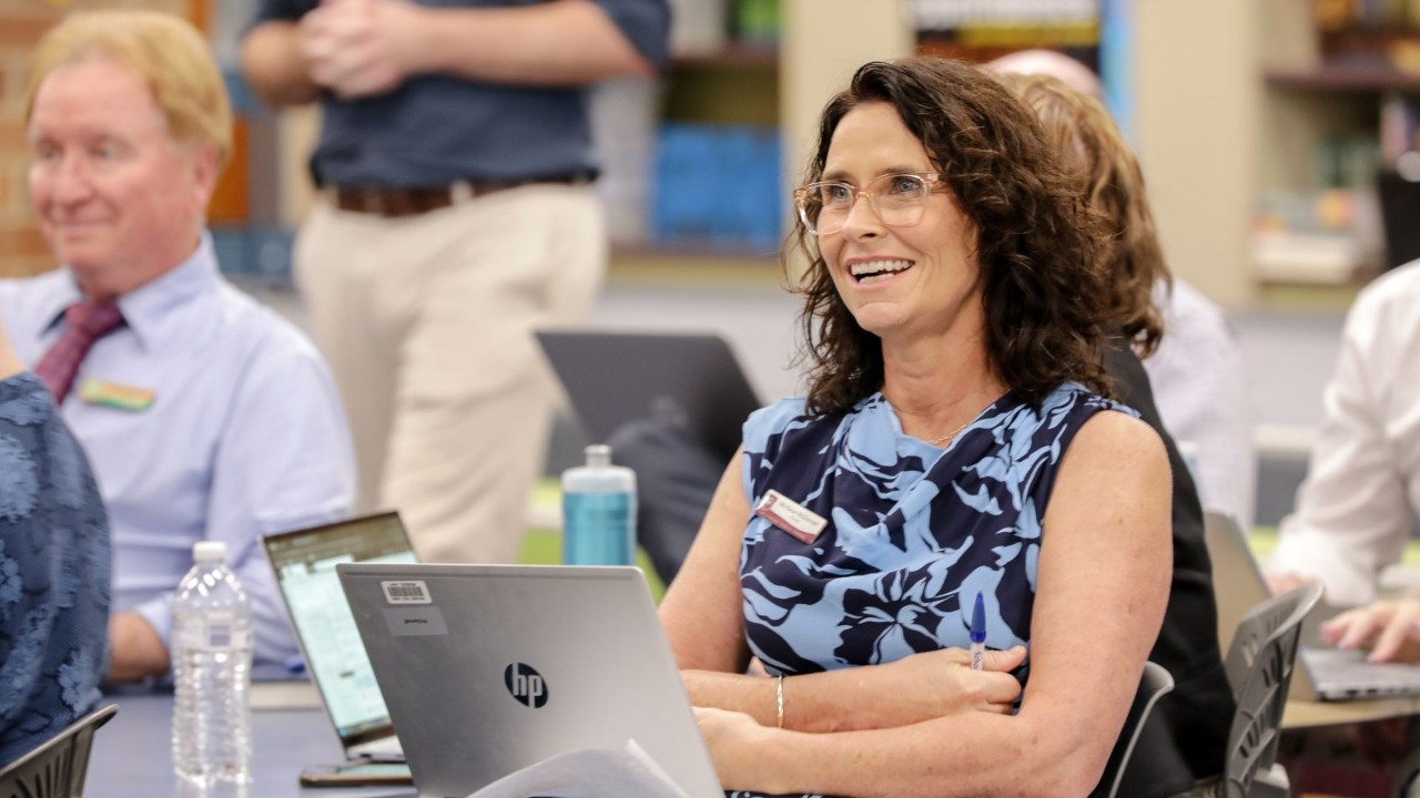 Lady sitting in front of a laptop smiling.