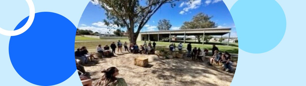 Students and teachers gathered around a yarning circle.